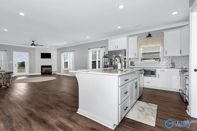 kitchen with stainless steel appliances, a sink, backsplash, an island with sink, and crown molding