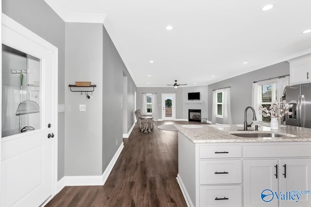 kitchen with a fireplace, a sink, white cabinetry, and light stone countertops