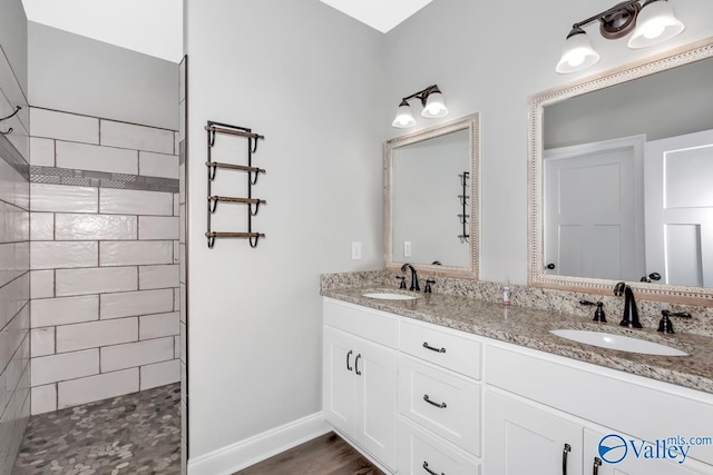 bathroom with double vanity, baseboards, walk in shower, and a sink