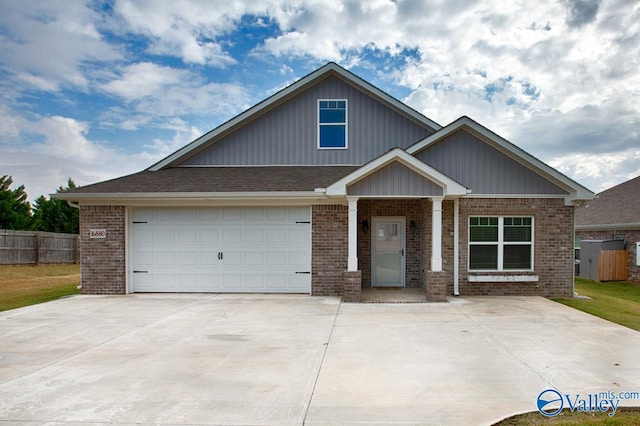 craftsman inspired home with a garage, brick siding, fence, and driveway