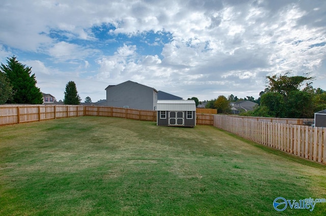 view of yard with an outbuilding, a fenced backyard, and a storage unit