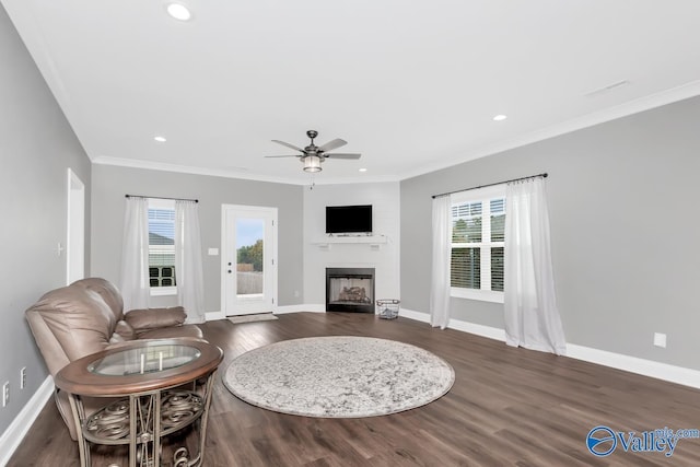 living area with crown molding, dark wood-style flooring, a fireplace, and baseboards