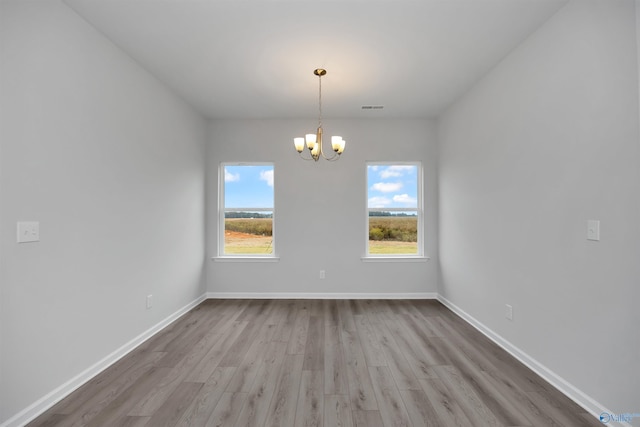 empty room with a chandelier and light hardwood / wood-style floors