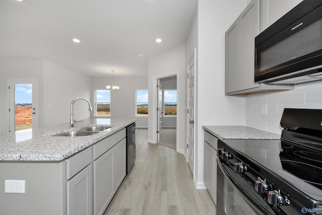 kitchen with sink, gray cabinetry, backsplash, black appliances, and a center island with sink