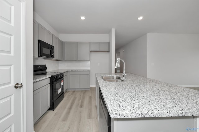 kitchen featuring gray cabinetry, sink, black appliances, and a center island with sink