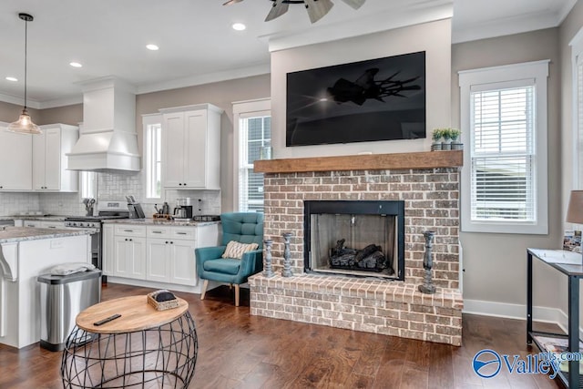 living room with dark hardwood / wood-style flooring, a fireplace, ceiling fan, and crown molding