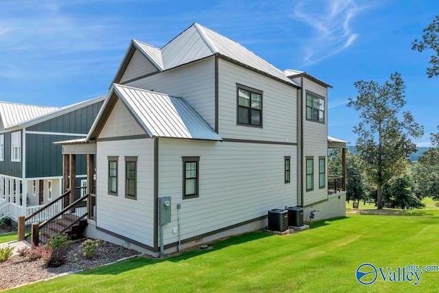 back of property featuring central air condition unit and a lawn