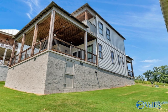 back of house with a balcony, a lawn, and ceiling fan