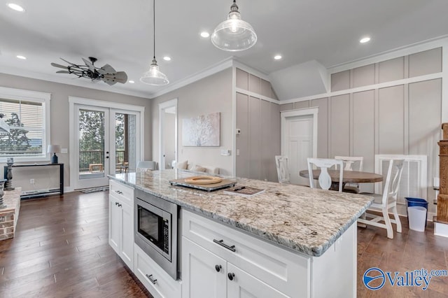 kitchen featuring a kitchen island, dark hardwood / wood-style floors, stainless steel microwave, and ornamental molding