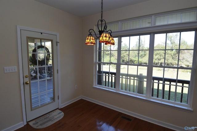 entryway with an inviting chandelier and dark wood-type flooring