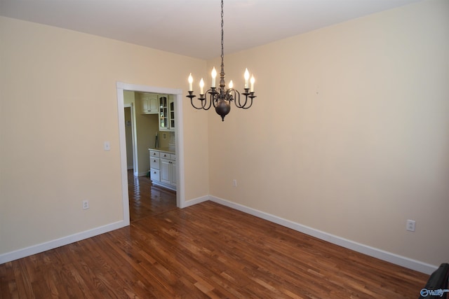 empty room with a chandelier and dark hardwood / wood-style flooring