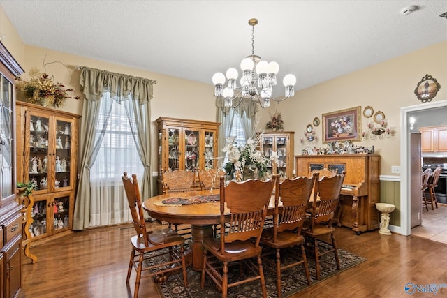 dining room featuring a notable chandelier, a textured ceiling, and wood finished floors