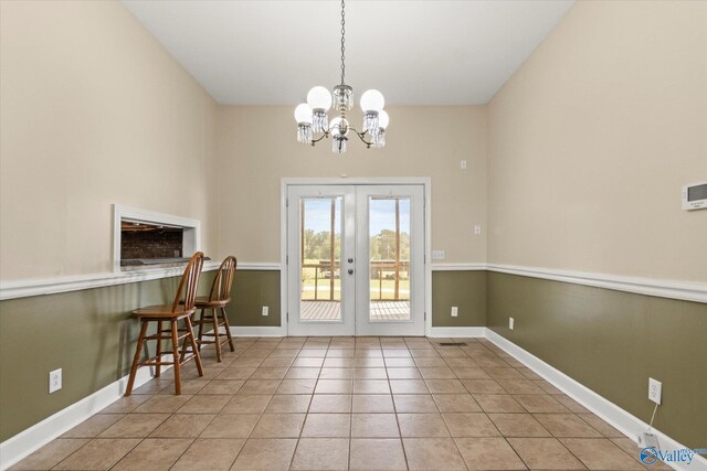 entryway with a notable chandelier, light tile patterned floors, and french doors