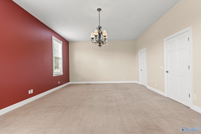 carpeted spare room featuring a chandelier