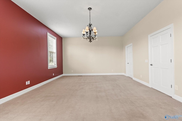 empty room featuring baseboards, light colored carpet, and an inviting chandelier