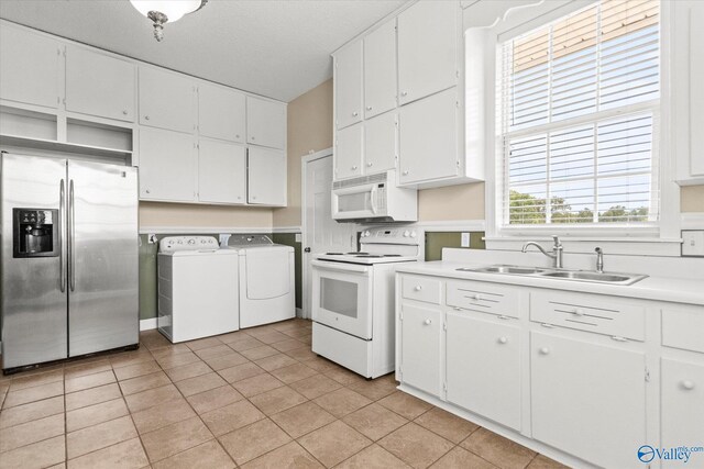 kitchen featuring light tile patterned flooring, white cabinets, white appliances, sink, and separate washer and dryer