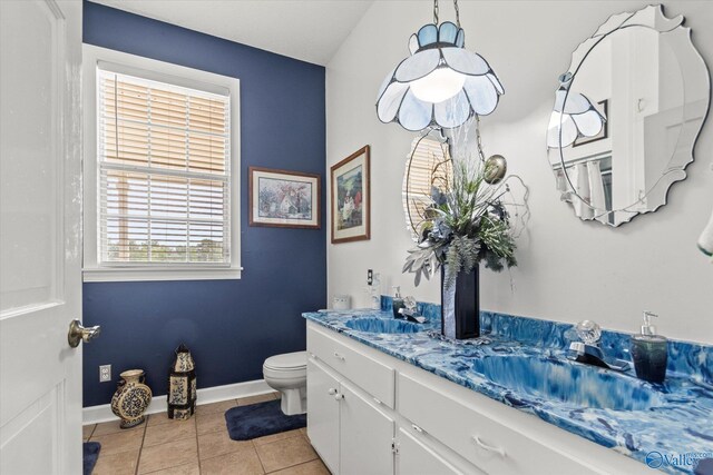 bathroom featuring toilet, tile patterned floors, and double sink vanity