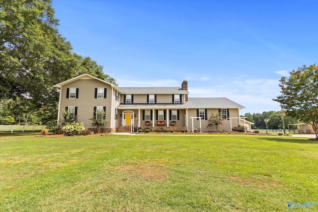 view of front of home with covered porch, a chimney, and a front yard