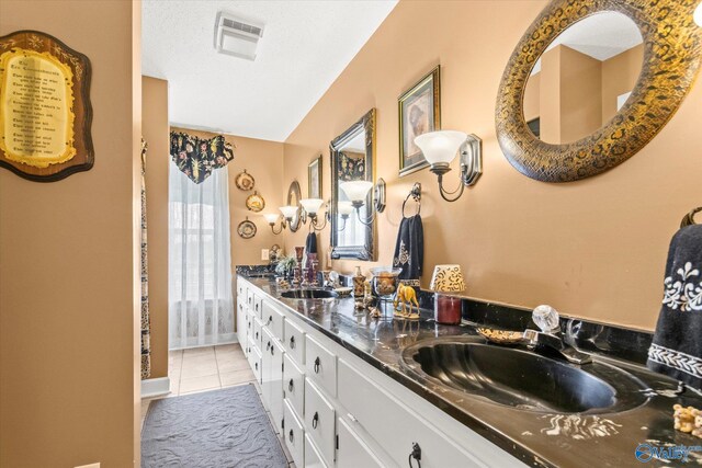 bathroom with tile patterned floors, a textured ceiling, and double sink vanity