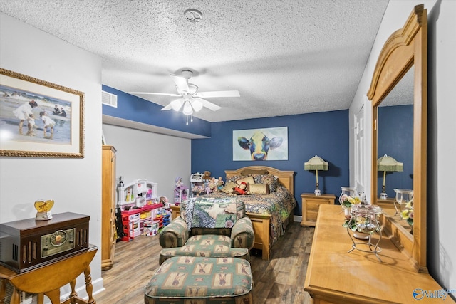 bedroom featuring a textured ceiling, wood finished floors, visible vents, and a ceiling fan