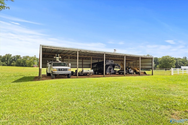 view of parking / parking lot featuring a carport, an outbuilding, fence, and driveway