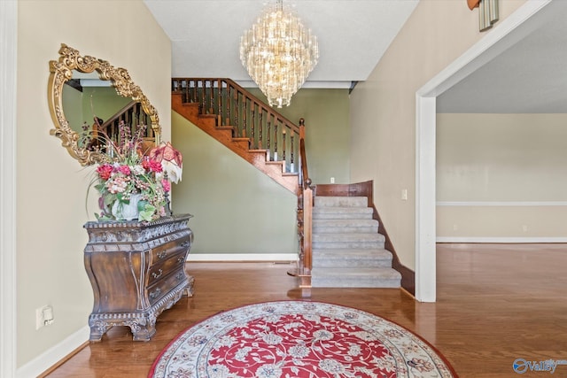 foyer entrance featuring a chandelier, stairs, baseboards, and wood finished floors