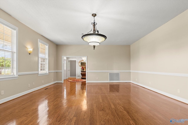 unfurnished dining area featuring wood finished floors, visible vents, and baseboards