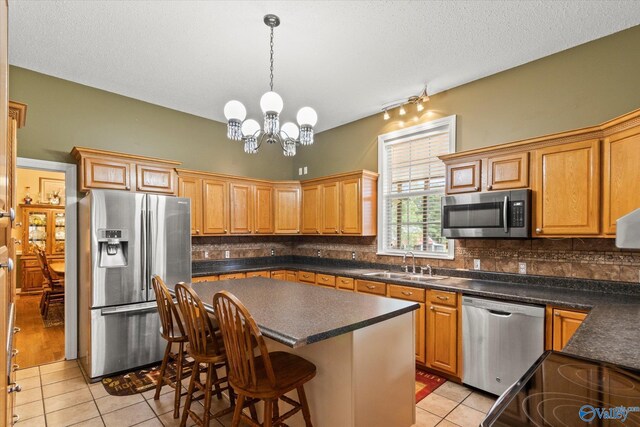 kitchen with a notable chandelier, light tile patterned floors, a center island, backsplash, and stainless steel appliances