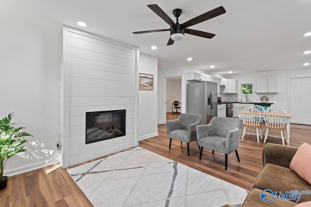 living room with sink, ceiling fan, light hardwood / wood-style flooring, and a fireplace