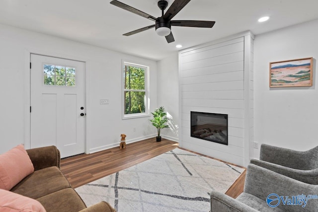 living room with ceiling fan, wood-type flooring, and a fireplace