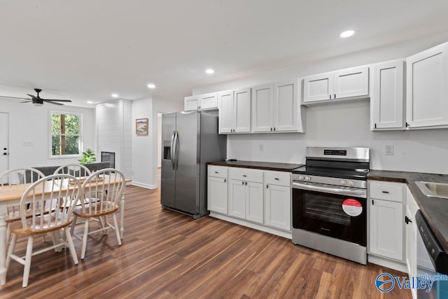 kitchen with white cabinets, ceiling fan, appliances with stainless steel finishes, dark wood-type flooring, and a fireplace