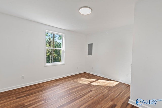 unfurnished room with electric panel and dark hardwood / wood-style floors