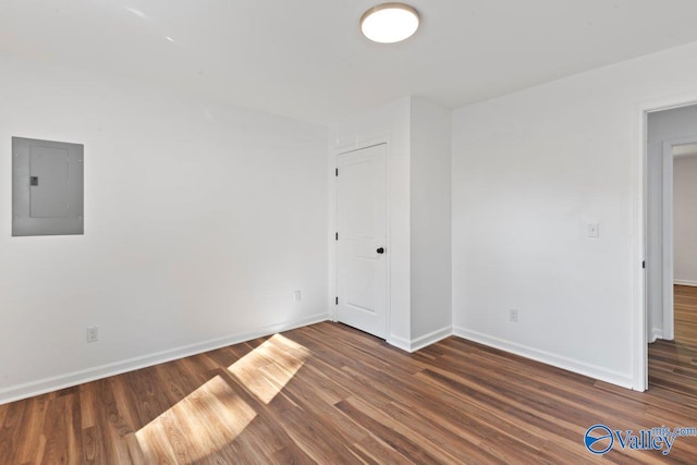 spare room with electric panel and dark wood-type flooring