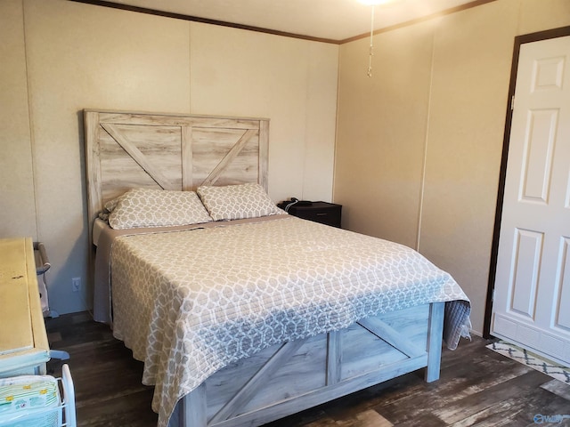bedroom with crown molding, a decorative wall, and wood finished floors