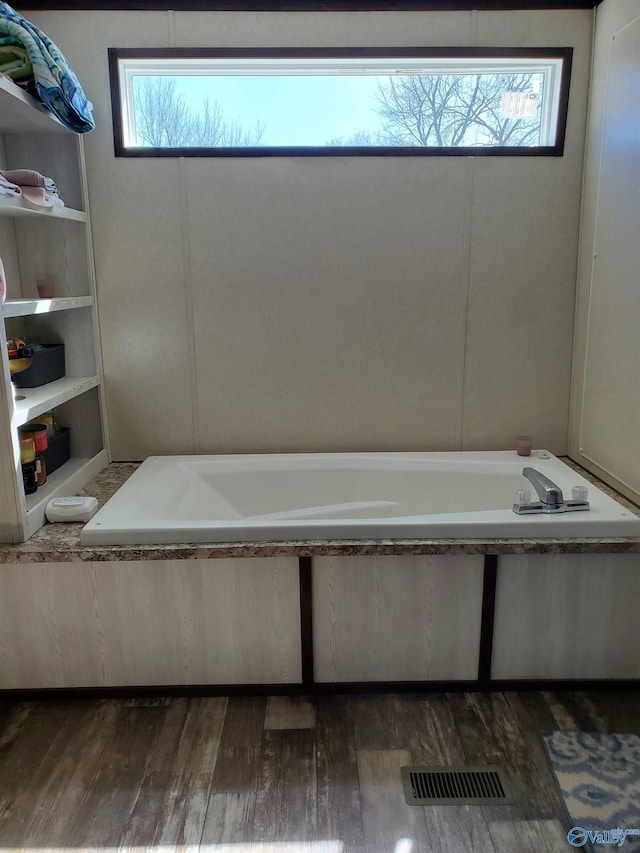 bathroom with visible vents, a garden tub, and wood finished floors