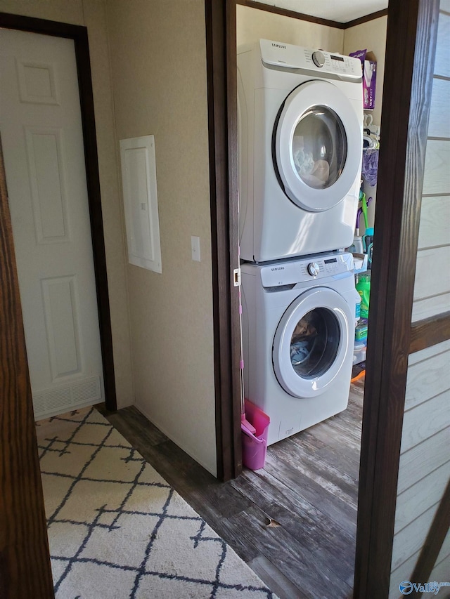 washroom featuring stacked washer and dryer, laundry area, and wood finished floors