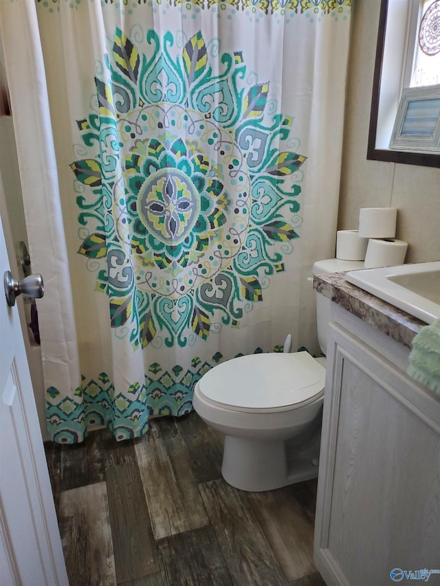 bathroom with toilet, curtained shower, vanity, and wood finished floors