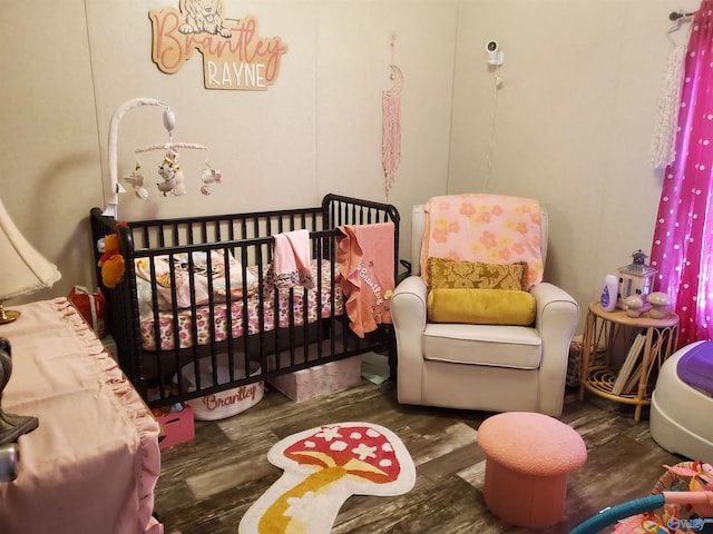 bedroom featuring wood finished floors and a crib