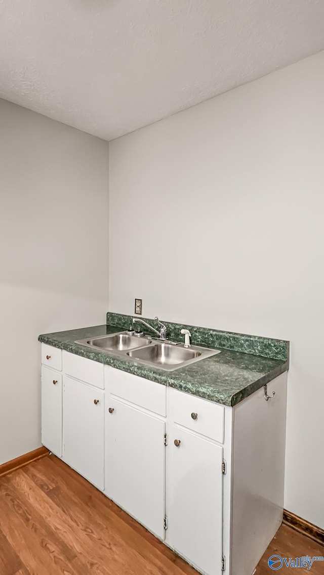 kitchen with sink, white cabinets, and light hardwood / wood-style flooring