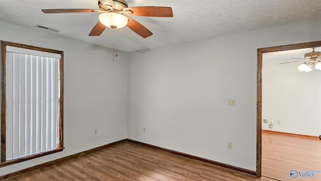 empty room with ceiling fan, hardwood / wood-style floors, and a textured ceiling