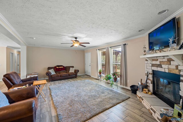 living room featuring a stone fireplace, light hardwood / wood-style floors, crown molding, a textured ceiling, and ceiling fan