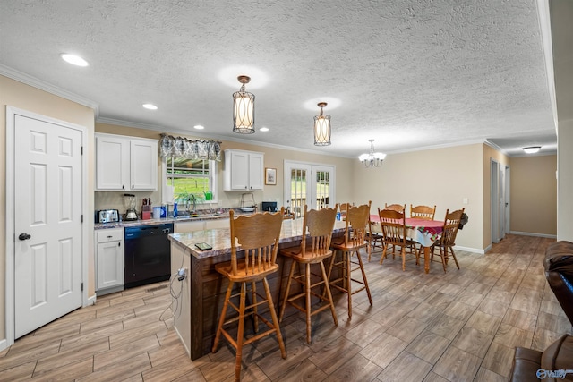 kitchen featuring a breakfast bar area, white cabinets, a kitchen island, black dishwasher, and pendant lighting