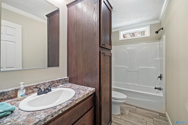 full bathroom featuring a textured ceiling, toilet, shower / tub combination, vanity, and ornamental molding