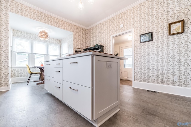 kitchen featuring visible vents, wallpapered walls, baseboards, and ornamental molding