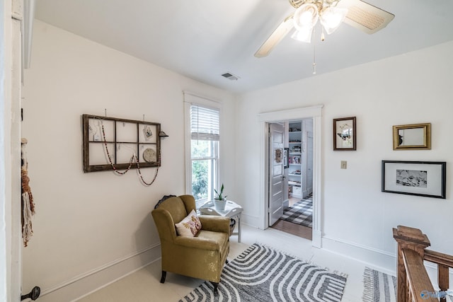 living area with visible vents, baseboards, and ceiling fan