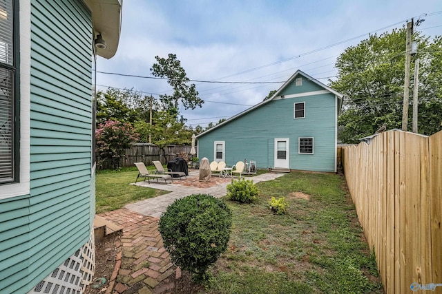 back of property featuring a patio, a fenced backyard, and a lawn