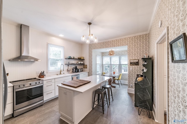 kitchen featuring a breakfast bar, a sink, appliances with stainless steel finishes, wall chimney exhaust hood, and wallpapered walls