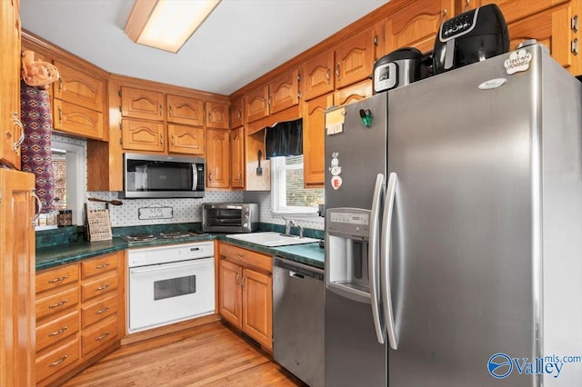 kitchen featuring appliances with stainless steel finishes, sink, backsplash, and light hardwood / wood-style floors