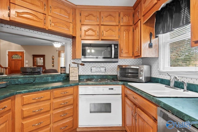 kitchen featuring sink, appliances with stainless steel finishes, decorative backsplash, and ceiling fan