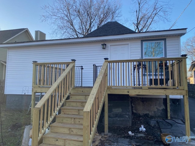 rear view of property featuring a shingled roof, a wooden deck, and stairs